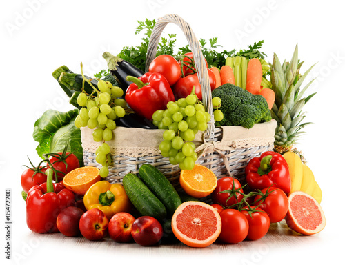 Organic vegetables and fruits in wicker basket isolated on white