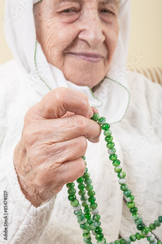 senior woman praying with prayer beads