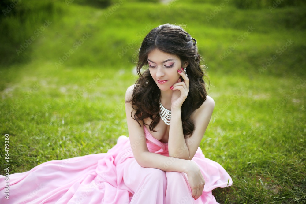 Attractive brunette young bride girl sitting on green grass at s Attractive brunette young bride girl sitting on green grass at s