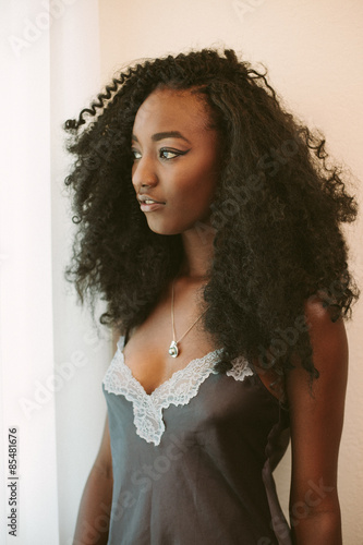 Young woman in nightie lingerie by bedroom window