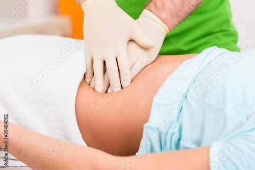 Practitioner at colon therapy massaging abdomen photo