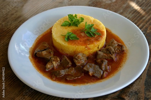 Sweet and sour beef liver cooked in red wine sauce served with polenta