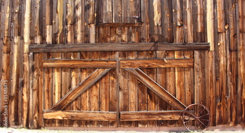 Wood Barn Doors – Front entrance of an old wooden farmhouse barn doors with metal wagon wheel 