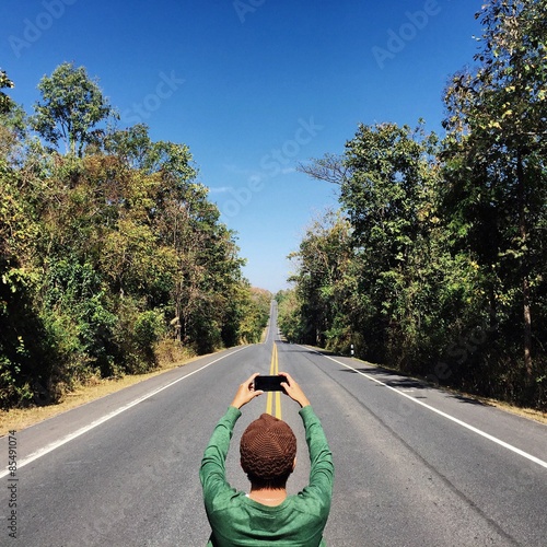 Man take a photo with the long road