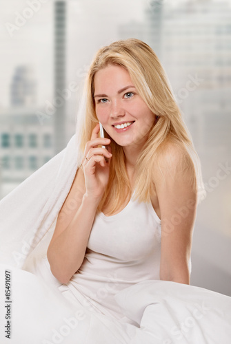  Radiant woman with phone on her bed