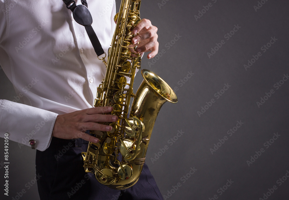 Naklejka premium A man plays the saxophone close up.