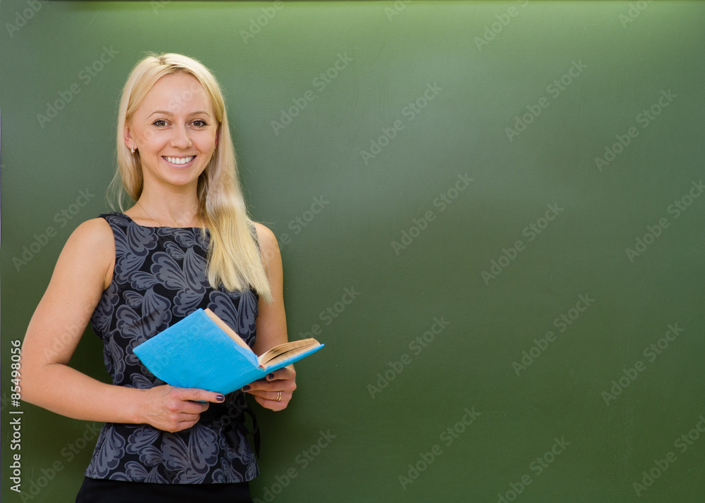 portrait of young teacher with books near chalkboard portrait of young teacher with books near chalkboard