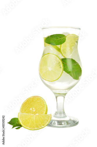 Lime into glass of water isolated on white