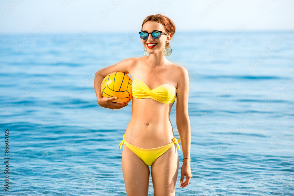 Woman with yellow ball in the sea