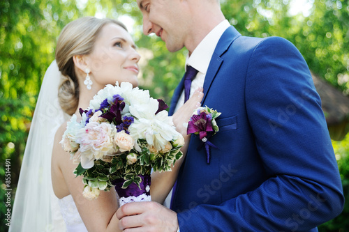 groom holding a wedding bouquet of peonies and roses