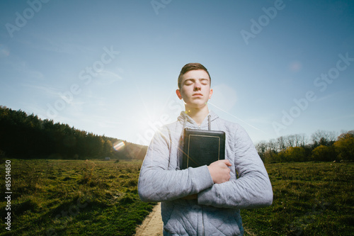 Young man reading Bible in a park