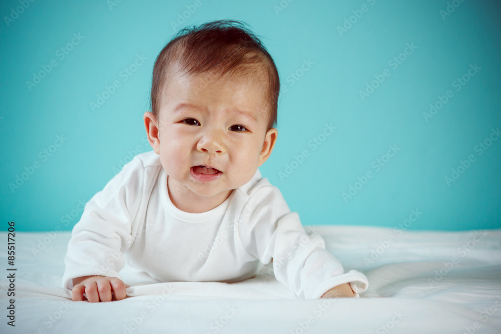 Cute baby girl lying at her stomach looking at camera, portrait Cute baby girl lying at her stomach looking at camera, portrait