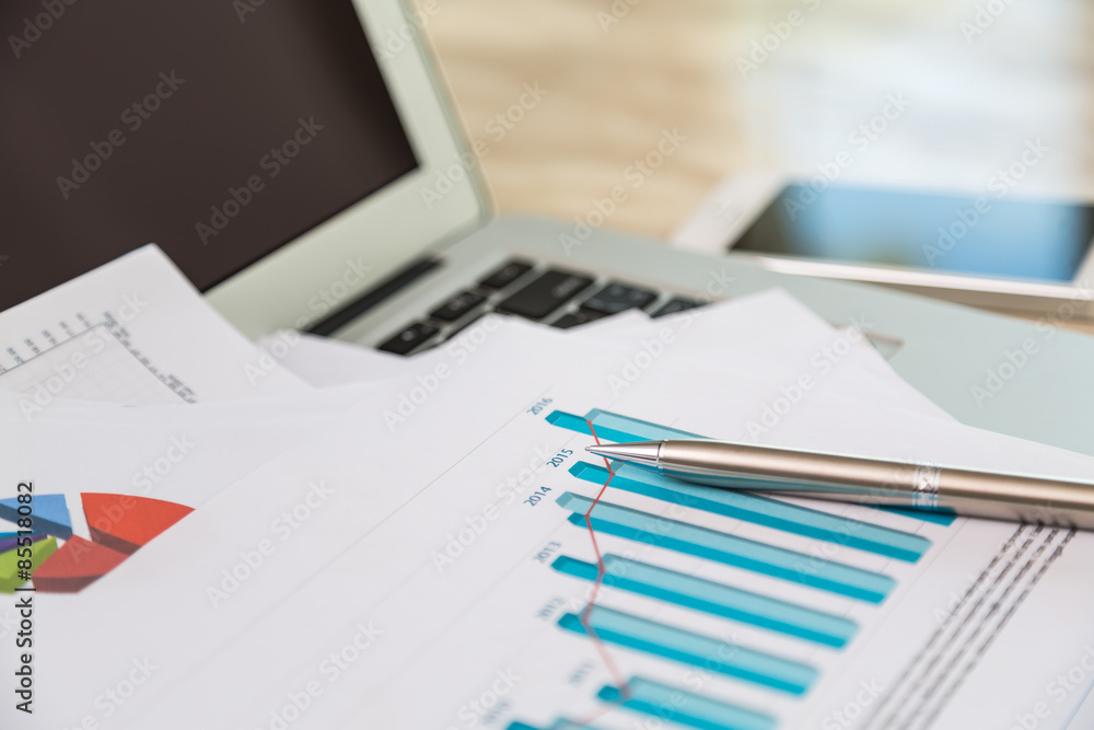 Financial charts on the table with laptop Financial charts on the table with laptop