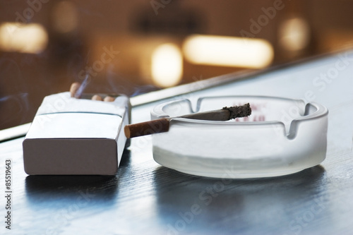 cigarette and ashtray on a table in a cafe