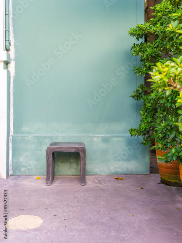 a chair with green wall and green trees