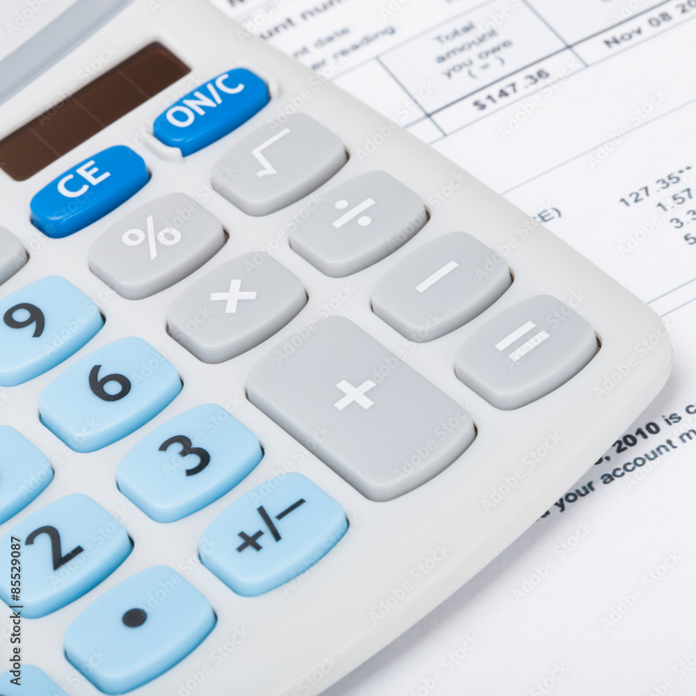 Calculator with utility bill under it - close up studio shot Calculator with utility bill under it - close up studio shot