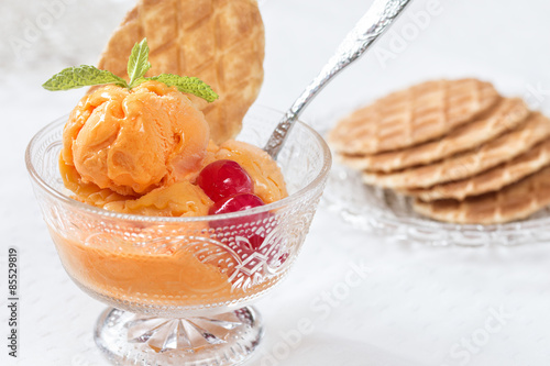 фотографія Orange ice crem served in a cup with waffles