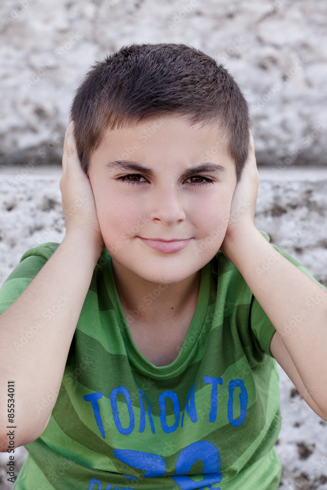 Portrait of a child covering his ears with his hands