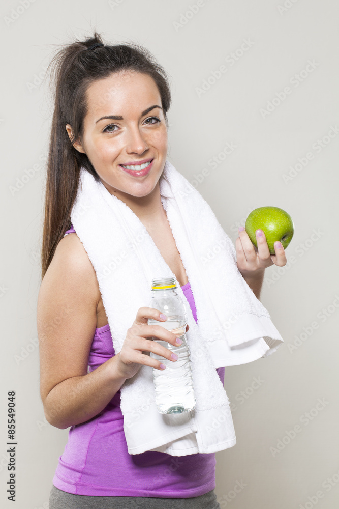 cute young fitness girl with white towel holding bottle of water and green apple as gym break cute young fitness girl with white towel holding bottle of water and green apple as gym break