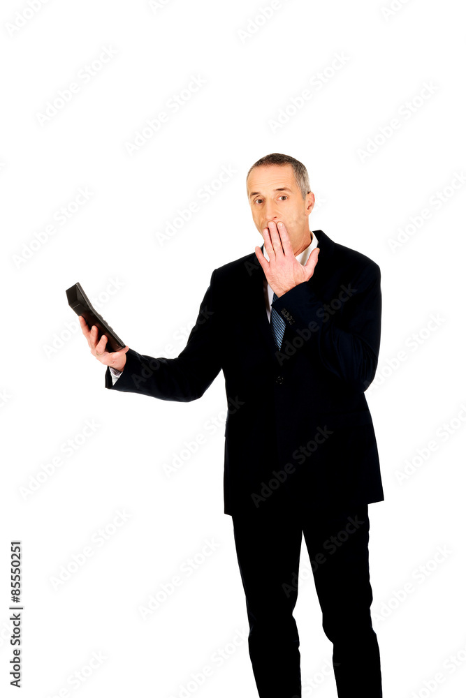 Shocked businessman holding a calculator Shocked businessman holding a calculator