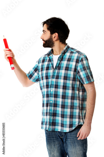 Young man pointing with big red pencil.