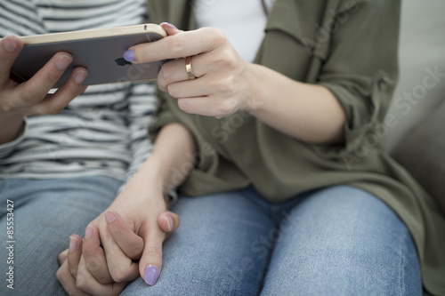 Women who are found together a smartphone hand in hand