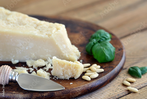 Parmesan - Parmesanmesser, Pinienkerne, Basilikum auf Holzbrett