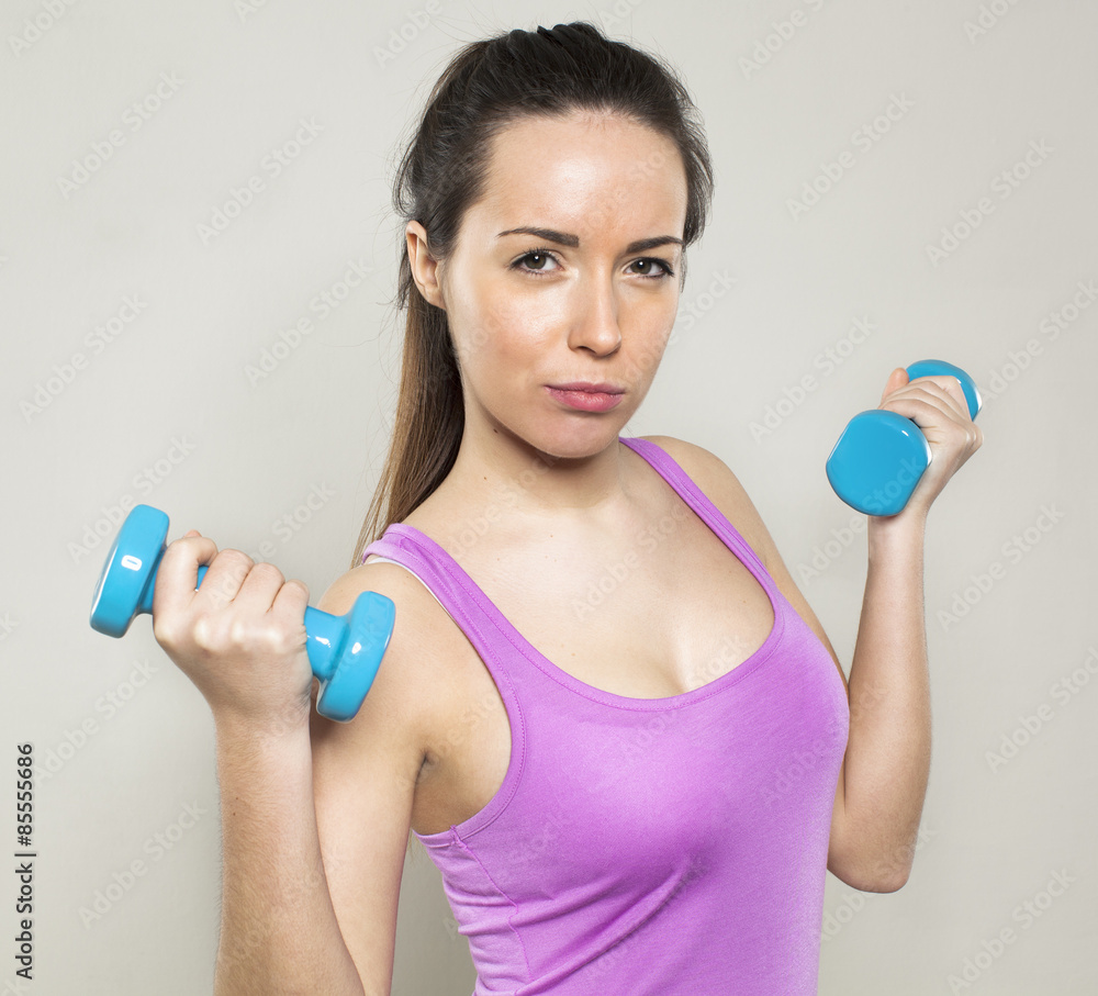 focused athletic woman wearing sportswear holding two dumbbells for workout and toned arm muscles focused athletic woman wearing sportswear holding two dumbbells for workout and toned arm muscles
