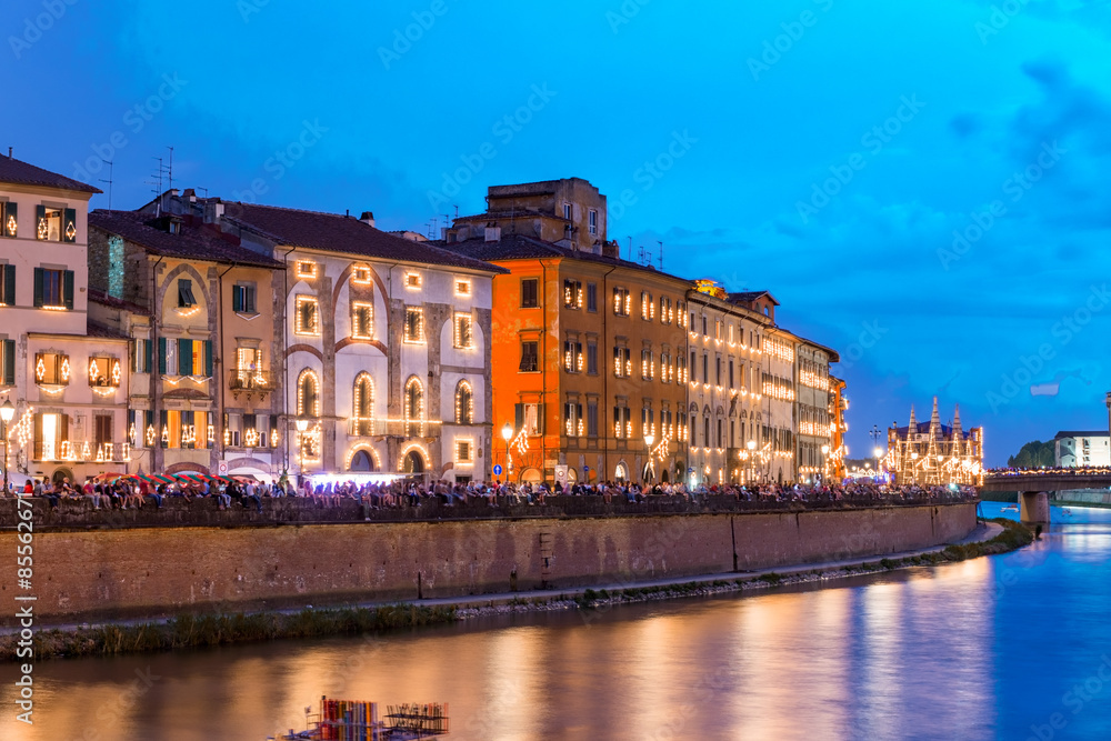 Pisa. Illuminated buildings along Arno river after sunset