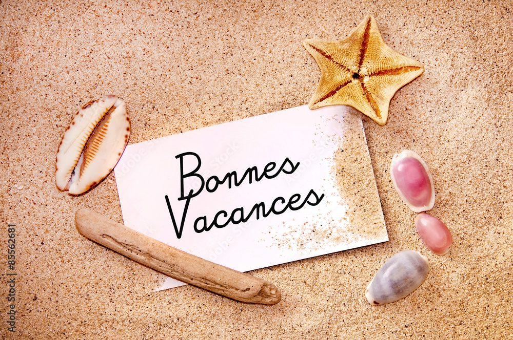Stockfoto Bonnes vacances écrit sur une carte dans le sable et coquillages Adobe Stock