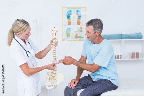 Doctor showing anatomical spine to her patient 