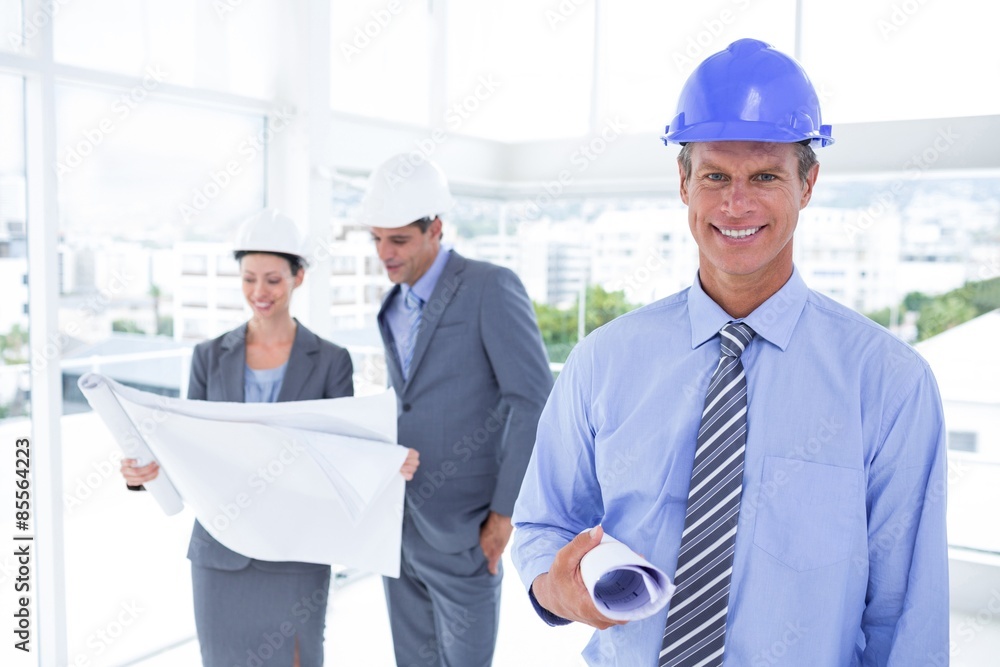 Businessmen and a woman with hard hats and holding blueprint Businessmen and a woman with hard hats and holding blueprint