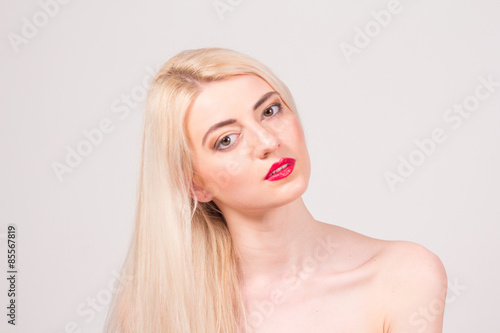 Fashion model posing at studio. Beautiful woman with long straight blond hair, red lips and make-up