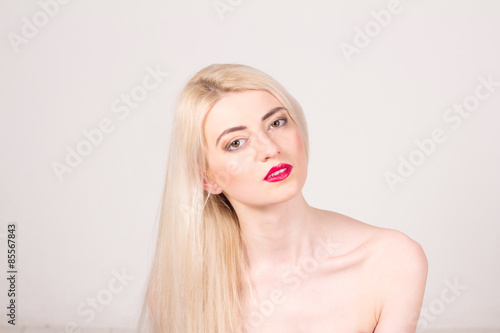 Fashion model posing at studio. Beautiful woman with long straight blond hair, red lips and make-up