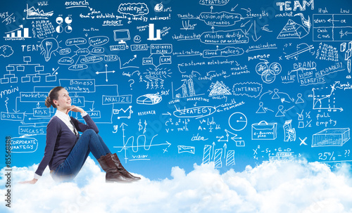 business woman sitting on the clouds and looking at a businessplan photo