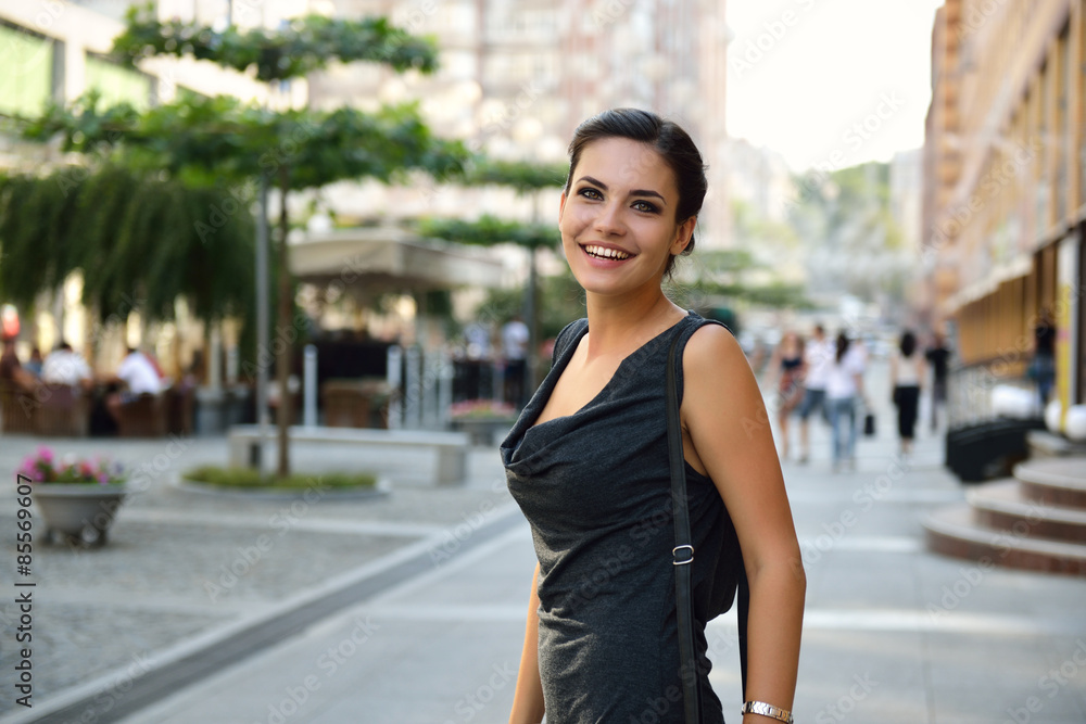Young attractive cheerful woman walking in city.