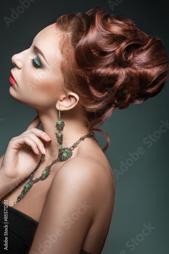 Beautiful red-hair girl with perfect skin and bright green makeup. Beauty face.portrait shot in the studio on a green background.