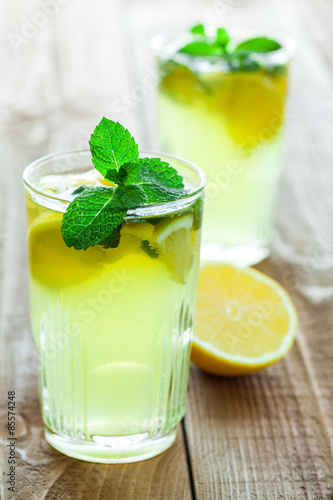 Εκτύπωση καμβά Two glasses of drink with lemon and fresh mint on wooden table.