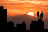 silhouette of high old building and the three child standing and looking forward on sky sunset background