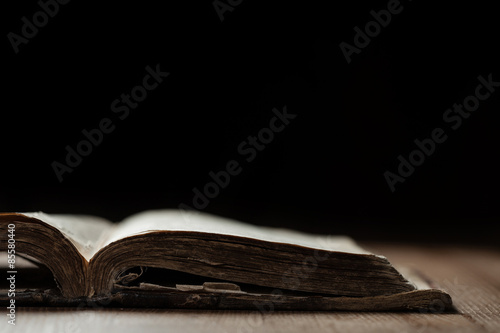 Leinwand Poster Bild einer alten Bibel auf Holzuntergrund in einem dunklen Raum mit geringer Tie