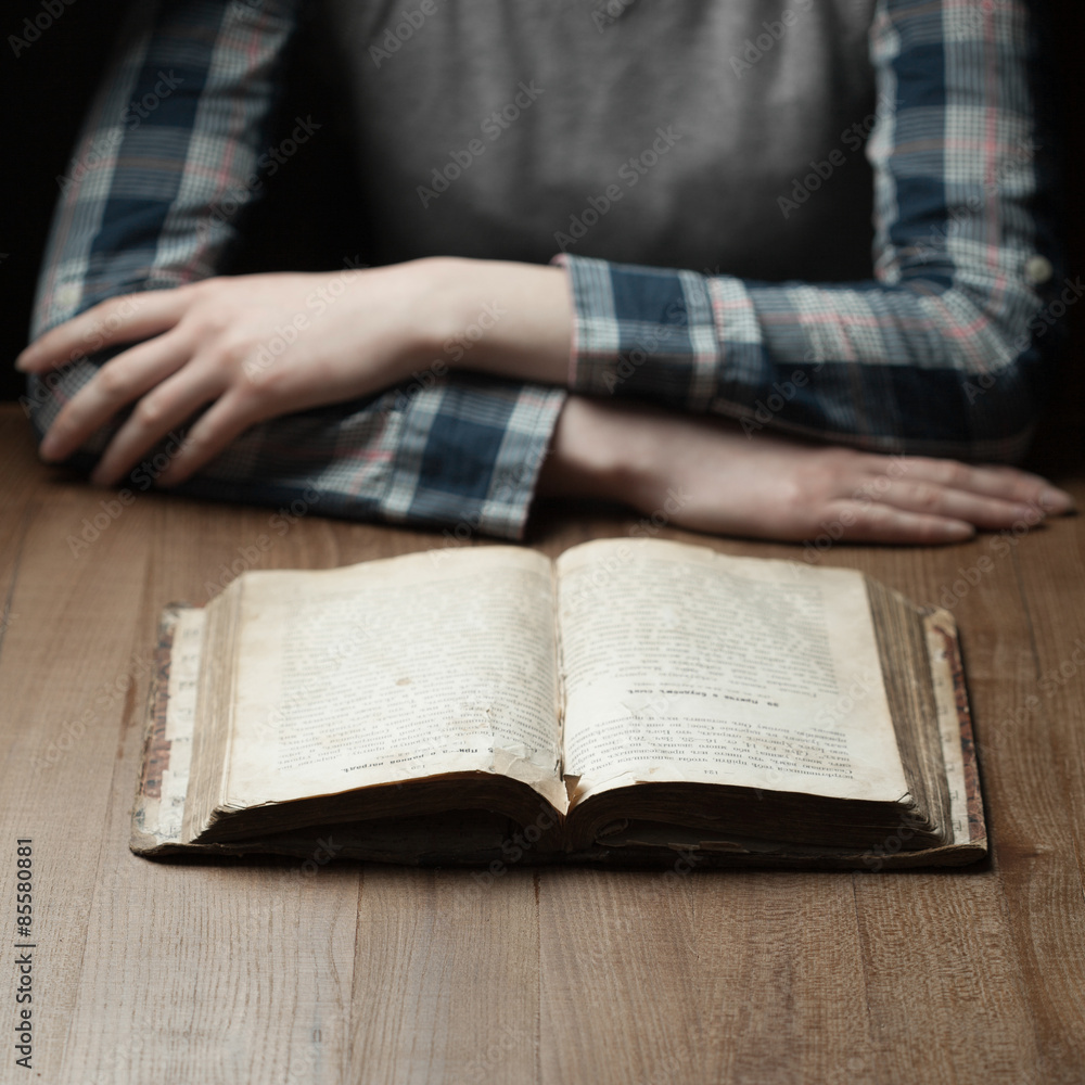 woman reading the bible in the darkness over wooden table woman reading the bible in the darkness over wooden table
