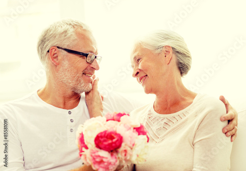 happy senior couple with bunch of flowers at home