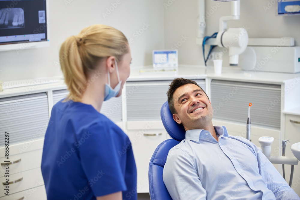 Obraz premium happy female dentist with man patient at clinic