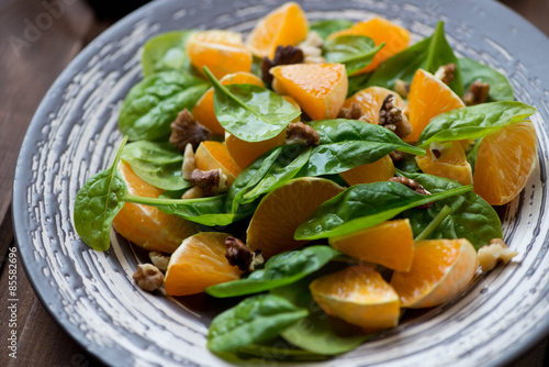 Close-up of tangerines, spinach leaves and walnuts salad