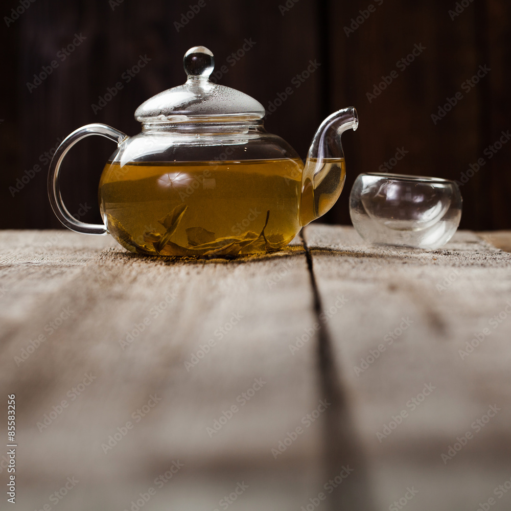green tea with jasmine in cup and teapot on wooden table green tea with jasmine in cup and teapot on wooden table