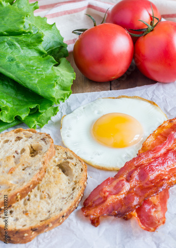 Making open face sandwich with egg  bacon  tomato and lettuce