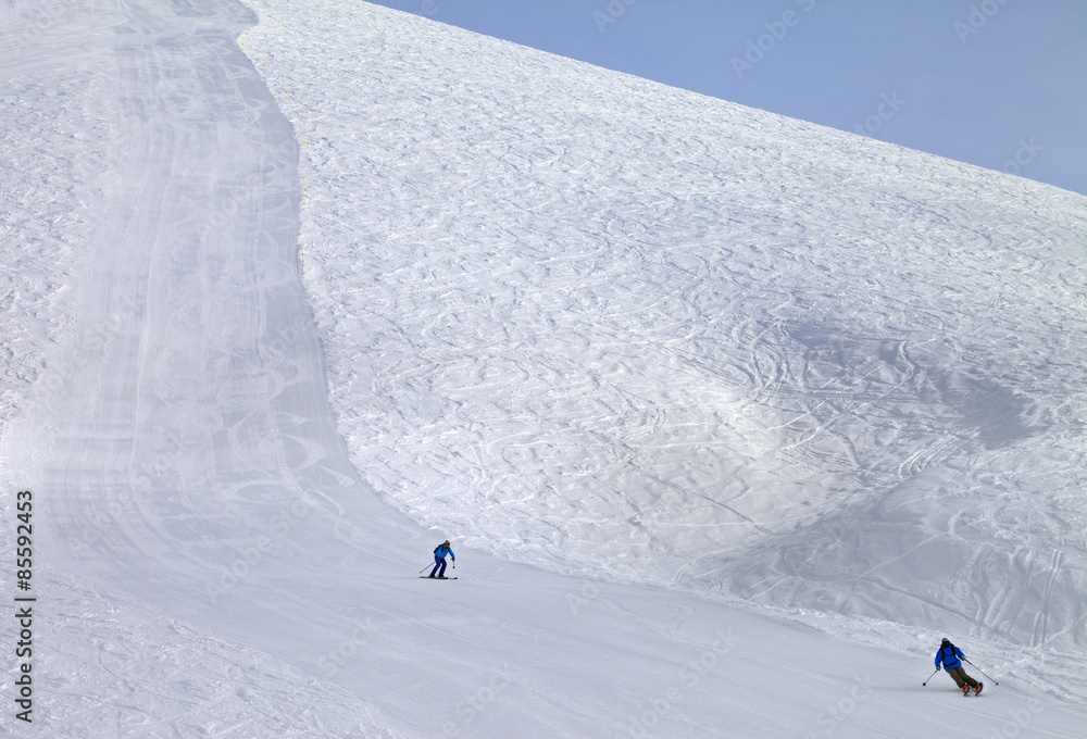 Ski slope and skiers at sun day