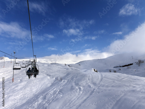 Chair-lift and off-piste slope in wind day