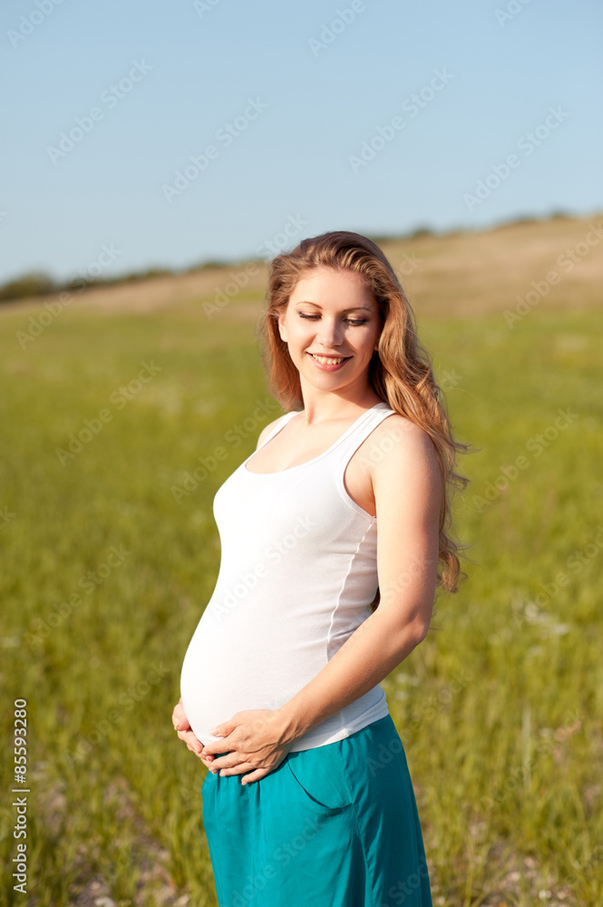 Happy pregnant woman resting in field outdoors. Smiling girl holding belly. Motherhood. Maternity. Happy pregnant woman resting in field outdoors. Smiling girl holding belly. Motherhood. Maternity.