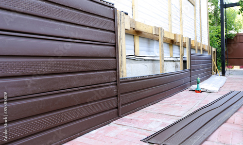 Installation of brown plastic siding on the facade